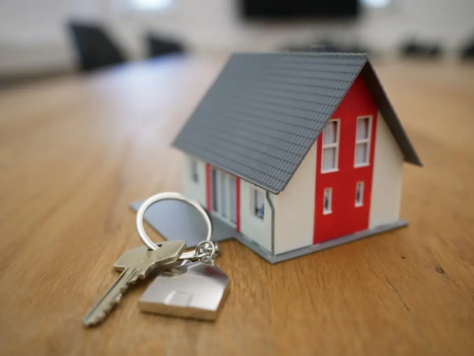 A set of house keys next to a miniature house